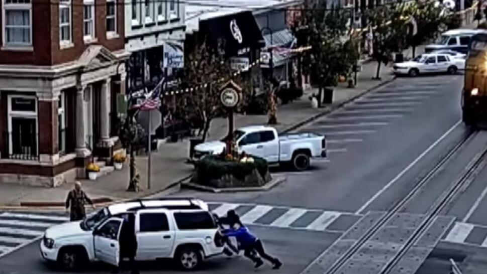 people pushing a white SUV off of train tracks